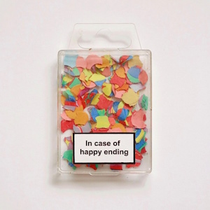 The fanmix's cover art. It shows a confetti-filled plastic container labelled In case of happy ending sitting on a white backdrop.